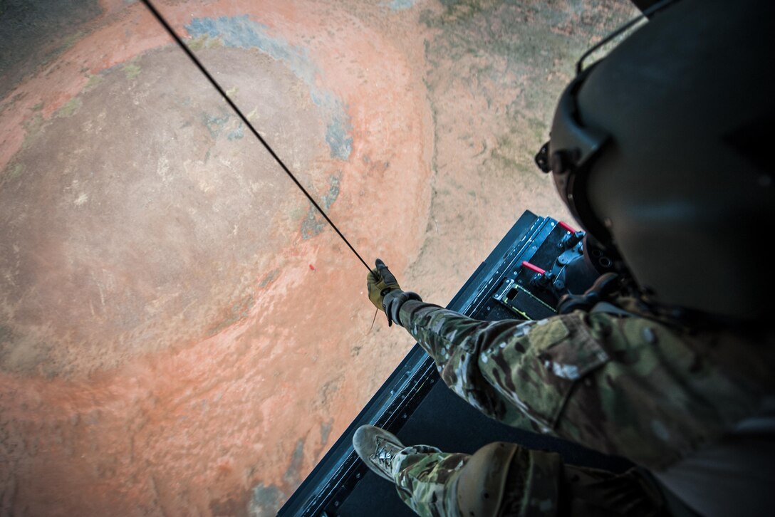 A flight engineer with the 8th Special Operations Squadron operates the hoist of a CV-22 Osprey tiltrotor aircraft above the Eglin Range, Fla., Nov. 8, 2016. The Osprey has been used operationally since 2006 to conduct long-range infiltration, exfiltration and resupply missions for special operations forces globally. (U.S. Air Force photo by Airman 1st Class Joseph Pick)