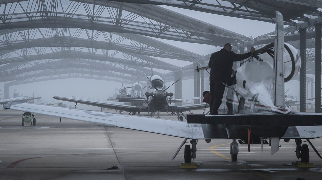 An L-3 Communications Holdings Inc. maintainer preps a T-6A Texan II as fog covers the flightline at Vance Air Force Base, Okla., Nov. 4, 2016. Since 1960, Vance AFB has been a joint civilian-military team, training more than 20,000 U.S. and allied nation pilots. (U.S. Air Force photo/David Poe)