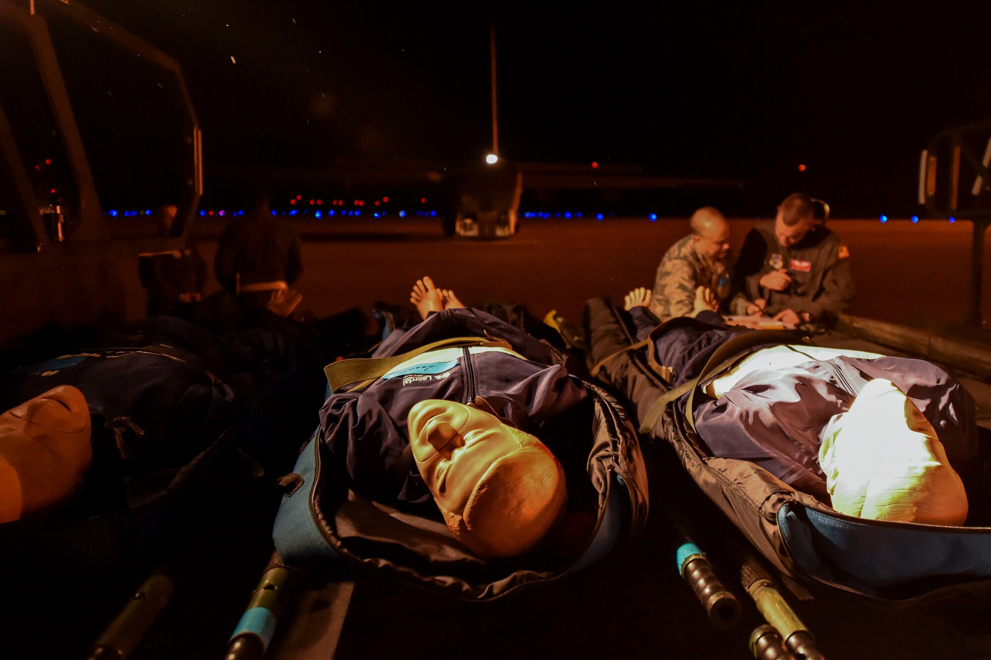 Simulated patients await evacuation as a team of medics from the 375th Aeromedical Evacuation Squadron discuss their plan to care for the patients during exercise Tropical Storm Greg, Nov. 8, 2016, at Alexandria, Louisiana.  The exercise was an example of how the U.S. Air Force provides support to local, state and federal authorities by performing a key role during crisis situations.  (U.S. Air Force Photo by Senior Airman Stephanie Serrano)