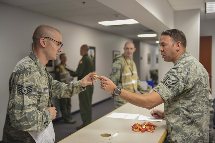 Staff Sgt. Bradley Thornton, 437th Maintenance Operations Squadron deficiency analyst, left, receives a pack of Starburst from Tech. Sgt. Hector Velazquezramos, 628th Medical Group diagnostics and therapeutic flight chief, right, at a point of distribution during a public health emergency exercise on Joint Base Charleston, South Carolina, Nov. 9, 2016. In the event of a real world incident, members would be given a flu vaccine if they hadn’t already received one as well as medication to combat the outbreak. To simulate that, those who participated in the base wide virus exercise were given the vaccination and candy to represent the medication.