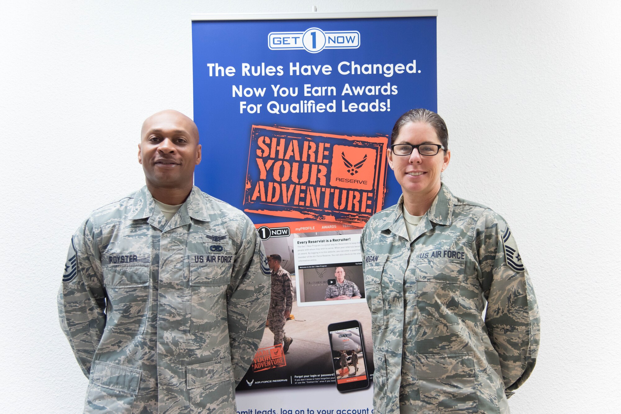 Master Sgt. Tavores Royster and Senior Master Sgt. Dominique Hogan, 403rd Wing recruiters, pose for a photo in front of their Get 1 Now poster. The 403rd Wing Recruiting Office won the Air Force Reserve Command Recruiting Service's Share Your Adventure Award Oct. 27. This award was presented for having the most ascessions through the Get 1 Now program.(U.S. Air Force photo/Staff Sgt. Heather Heiney) 