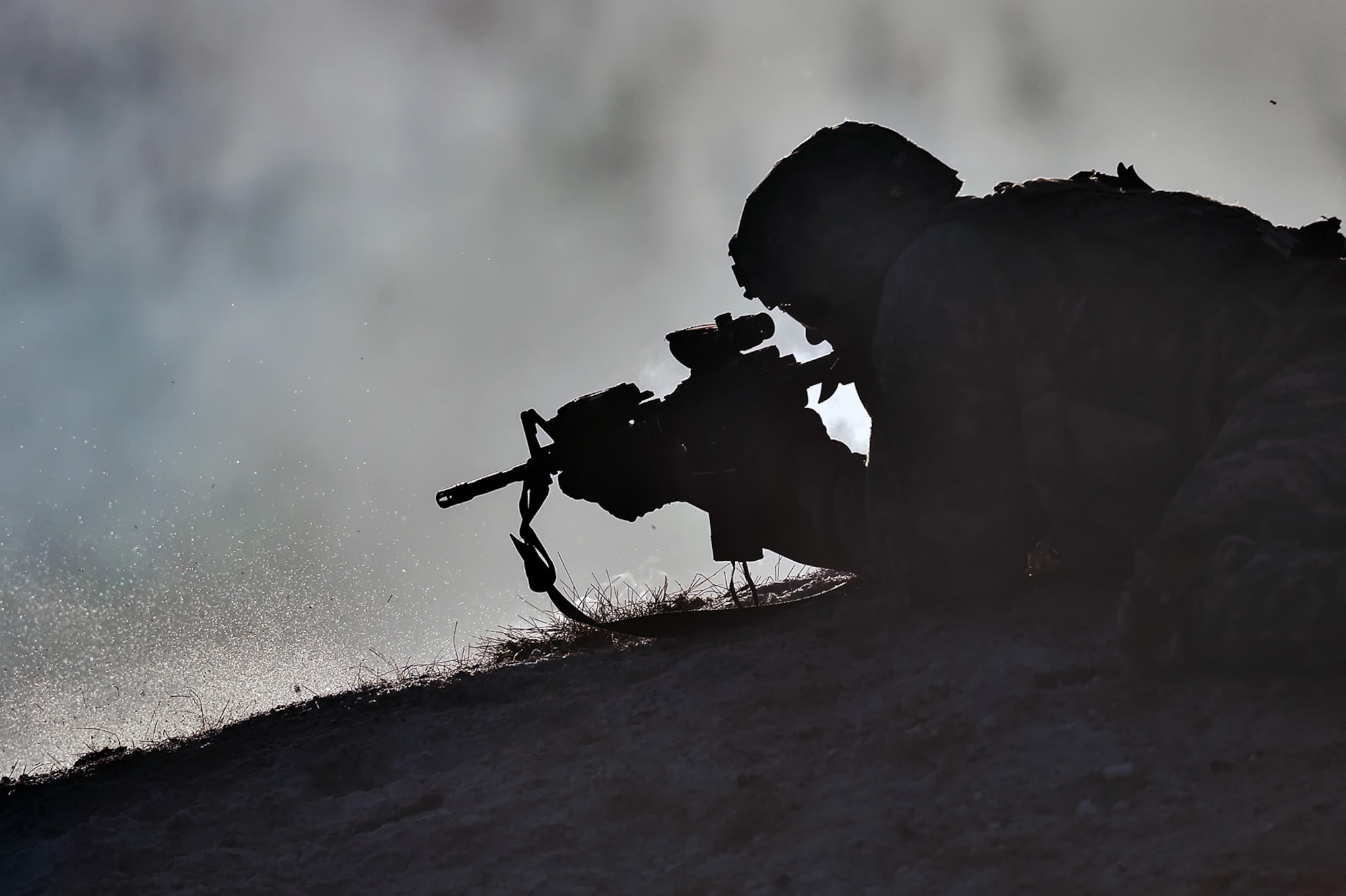 A paratrooper assigned to Baker Company, 3rd Battalion, 509th Parachute Infantry Regiment, 4th Infantry Brigade Combat Team (Airborne), 25th Infantry Division, U.S. Army Alaska, fires his M4 carbine through smoke and haze during live-fire and movement-to-contact operations on the Infantry Squad Battle Course at Joint Base Elmendorf-Richardson, Alaska, Nov. 8, 2016. The soldiers focused on core infantry skills such as fire team movement, communication, shifting fire, and once on the objective identifying and eliminating weapons caches and treating and evacuating casualties.  