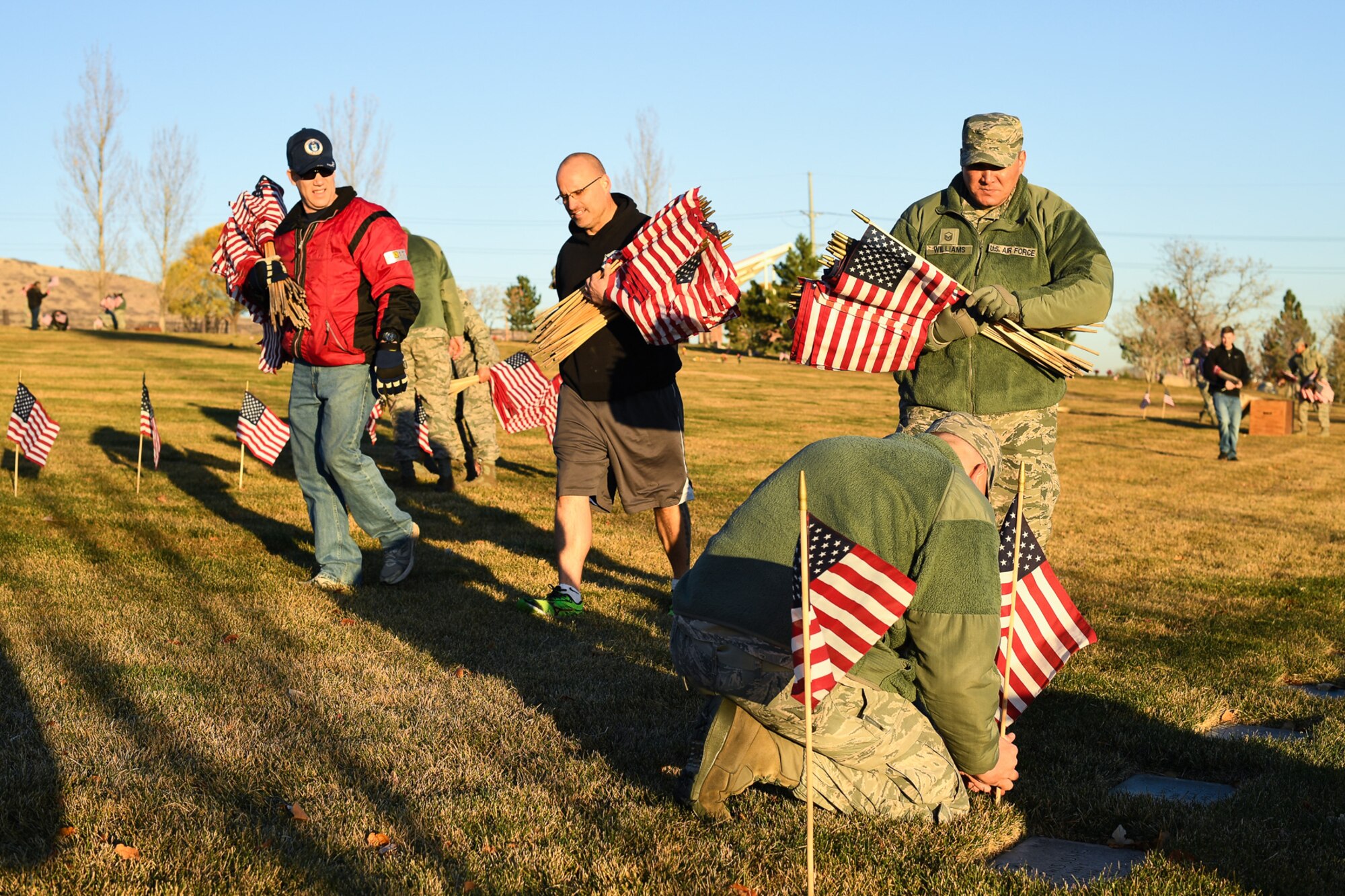 Team Hill Airmen begin placing flags beside grave sites during a Veterans Day recognition project Nov. 10 at the Utah Veterans Memorial Cemetery in Bluffdale. Airmen and family members from Hill AFB participated in a flag-placing detail in preparation for Veterans Day. (U.S. Air Force photo by R. Nial Bradshaw) 