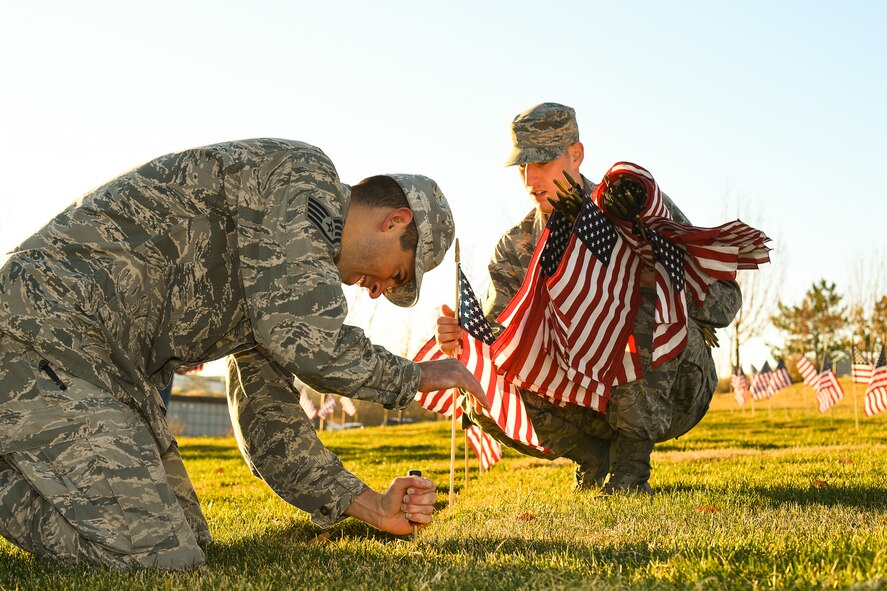 Staff. Sgt. Shane O'Brian, 388th Maintenance Squadron, makes a hole in the ground with a screwdriver while Staff Sgt. Skyler Williams, 388th MXS, places flags beside resting-place markers at the Utah Veterans Memorial Cemetery in Bluffdale, Nov. 10. (U.S. Air Force photo by R. Nial Bradshaw)