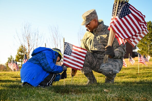 Master Sgt. Timothy Mason, 372nd Training Squadron, holds a bundle of flags while his son Marcus places a flag beside a cemetery marker at the Utah Veterans Memorial Cemetery in Bluffdale, Nov. 10. 2016. Airmen and family members from Hill Air Force Base participated in a flag-placing detail in preparation for Veterans Day. (U.S. Air Force photo by R. Nial Bradshaw) 