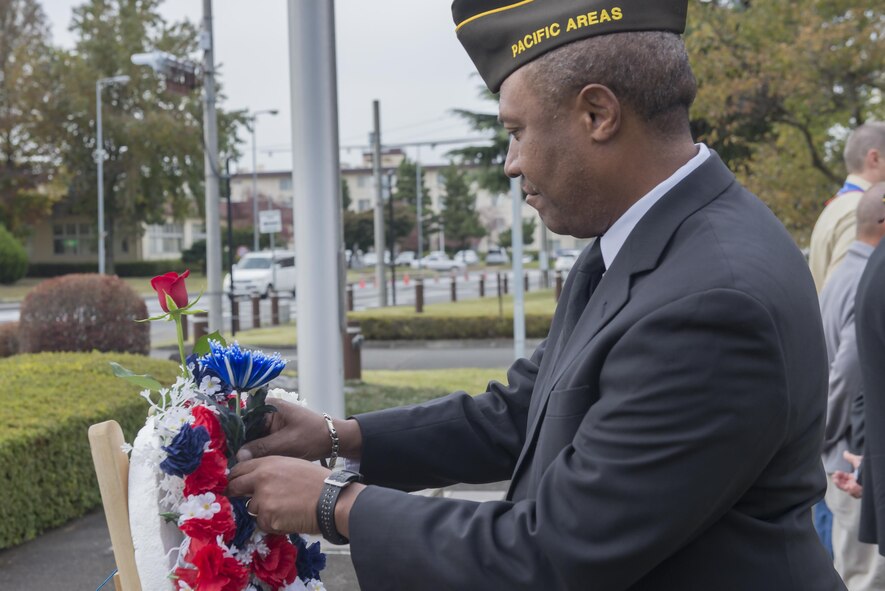 A member of the Veterans of Foreign Wars places a blue flower on a monument during the three flower ceremony at Yokota Air Base, Japan, Nov. 10, 2016. The three flowers each have a different meaning. The red rose represents those who have died in defense of their country, the white celebrates future service members and the blue immortalizes the deeds of soldiers, sailors, airmen and marines. (U.S. Air Force photo by Senior Airman David C. Danford/Released)