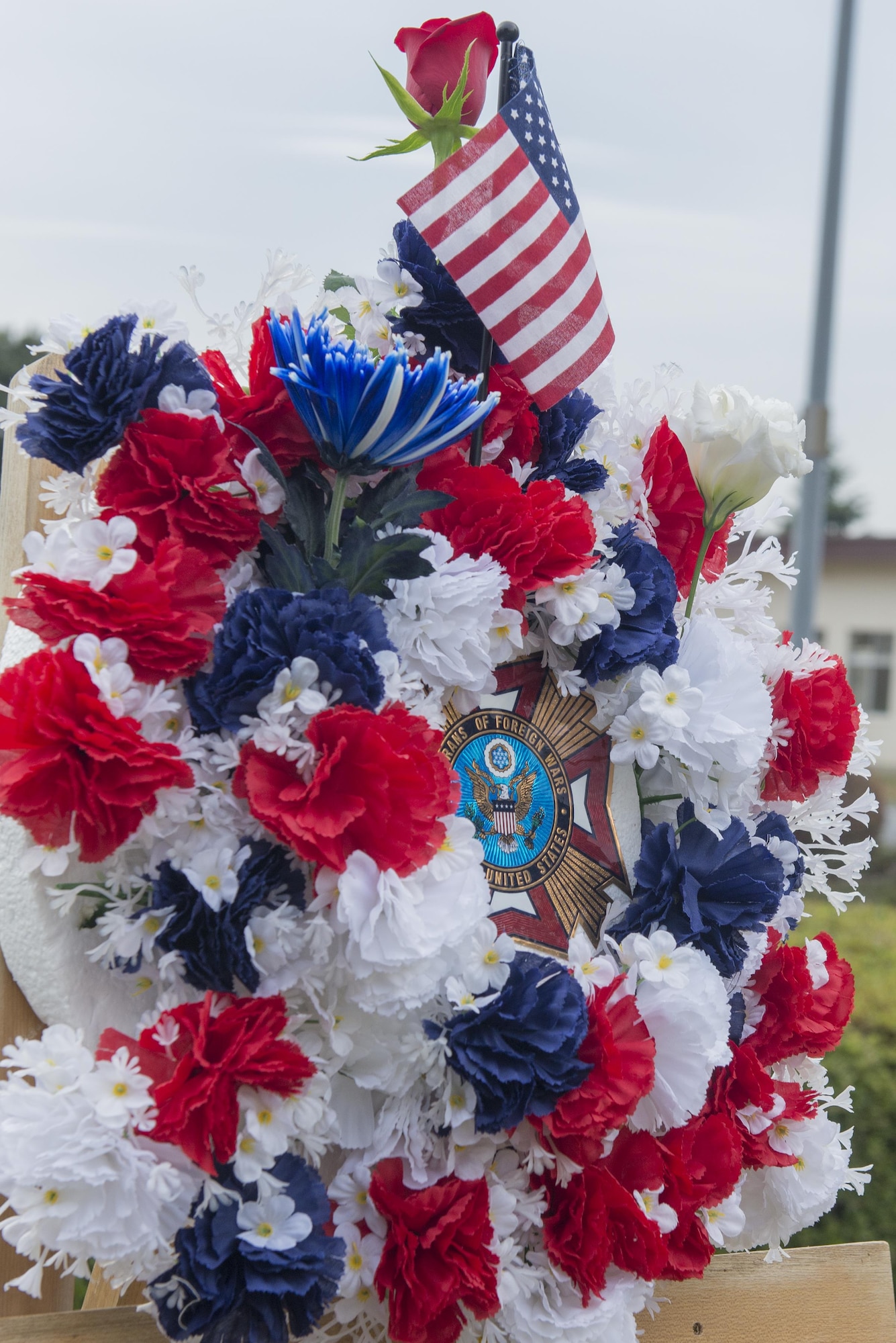 A complete three flower ceremonial wreath sits on an easel during a Veterans Day ceremony at Yokota Air Base, Japan, Nov. 10, 2016. The three flowers each have a different meaning. The red rose represents those who have died in defense of their country, the white celebrates future service members and the blue immortalizes the deeds of soldiers, sailors, airmen and marines. (U.S. Air Force photo by Senior Airman David C. Danford/Released)