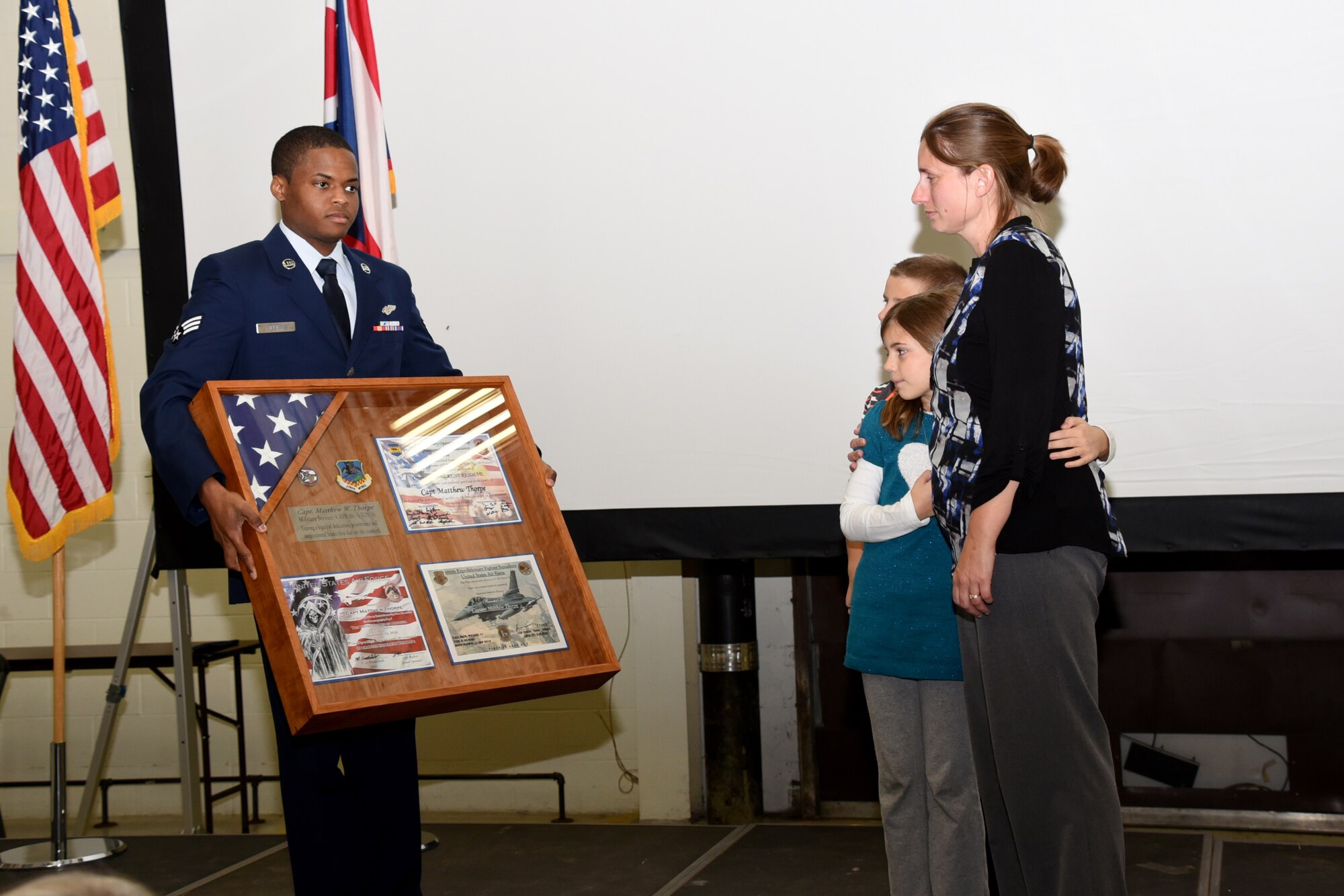 Mrs. Kate Thorpe and her children receive a shadowbox with a flag that has been flown in aircraft involved in combat missions with certificates at a memorial service for her deceased husband, Capt. Matthew Thorpe at the Springfield Air National Guard Base, Ohio Nov. 6.
Thorpe passed away suddenly this past Summer of natural causes.(U.S. Air National Guard photo by Airman 1st Class Anthony Le)