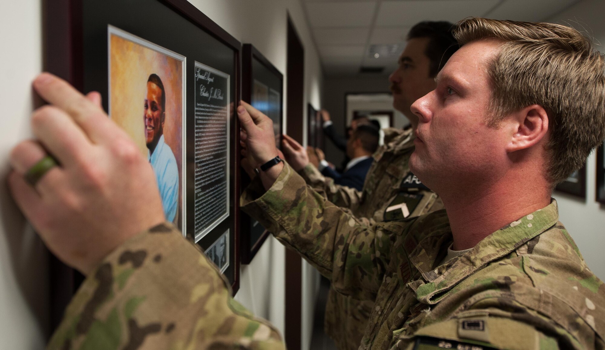 Special Agent Bradley Allen, 25th Expeditionary Field Investigation Squadron agent, hangs the portrait of a deceased Air Force Office of Special Investigations portrait during the 25th Expeditionary Field Investigation Squadron’s fallen heroes dedication memorial at Ramstein Air Base, Germany, Nov. 10, 2016. The portraits contained biographies of the servicemember that told their story and the legacy they left behind. Veteran’s Day is a celebration to honor America's veterans for their patriotism, love of country, and willingness to serve and sacrifice, even if it means their lives. According to a recent Congressional Research Service report, more than 6,500 U.S. service members have lost their lives in post-9/11 conflicts in Iraq and Afghanistan. (U.S. Air Force photo by Airman 1st Class Lane T. Plummer)