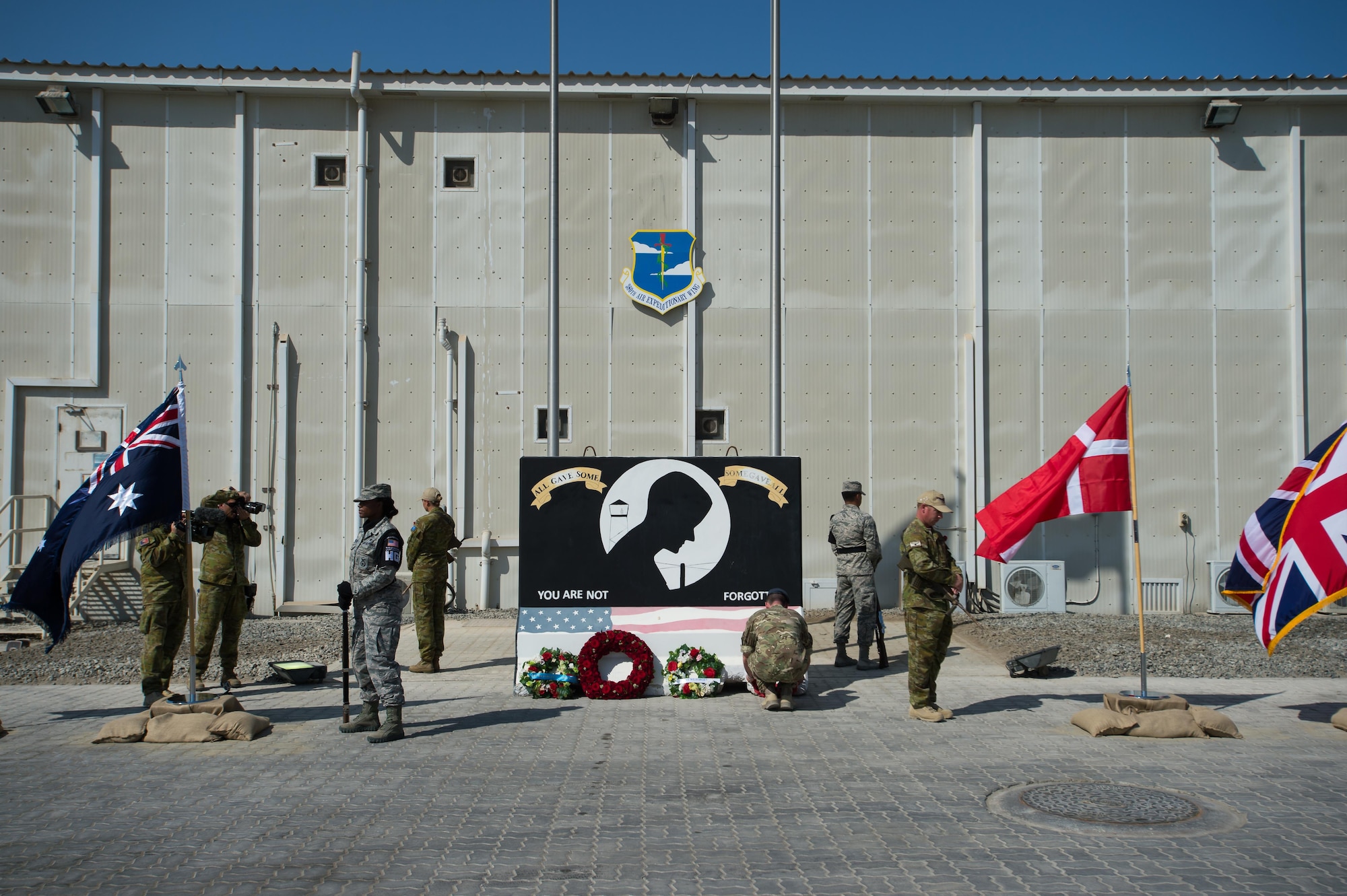 A deployed United Kingdom Coalition service member places a wreath on the base of a memorial, Nov. 11, 2016 at an undisclosed location in Southwest Asia. During the joint coalition ceremony, four nations participated in the remembrance of living and fallen veterans.  (U.S. Air Force photo by Senior Airman Tyler Woodward)