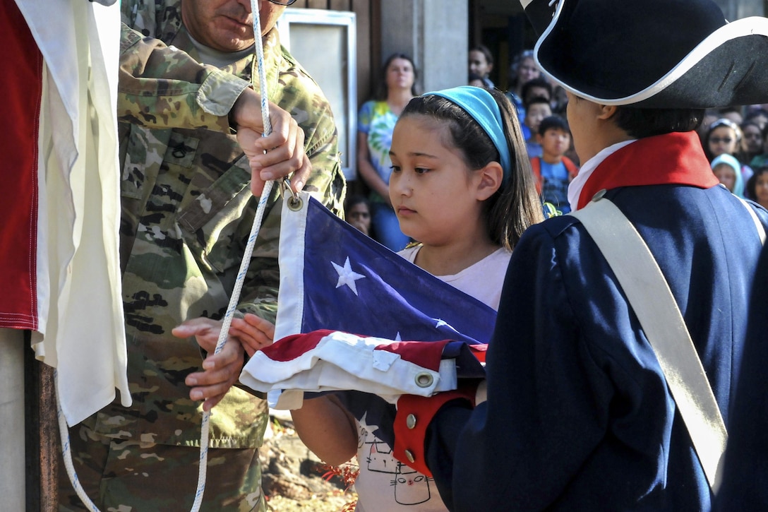 Amy Pietromanco helps raise the U.S. flag during a flag-raising ceremony at Christa McAuliffe Elementary School in Saratoga, Calif., Nov. 10, 2016. Army Staff Sgt. Juan Martinez, left, and Sgt. Arleen Banioza, right, assisted the fourth grader. Martinez, a human resources specialist, and Banioza, a color guard noncommissioned officer, are assigned to the 63rd Regional Support Command. Army photo by Alun Thomas