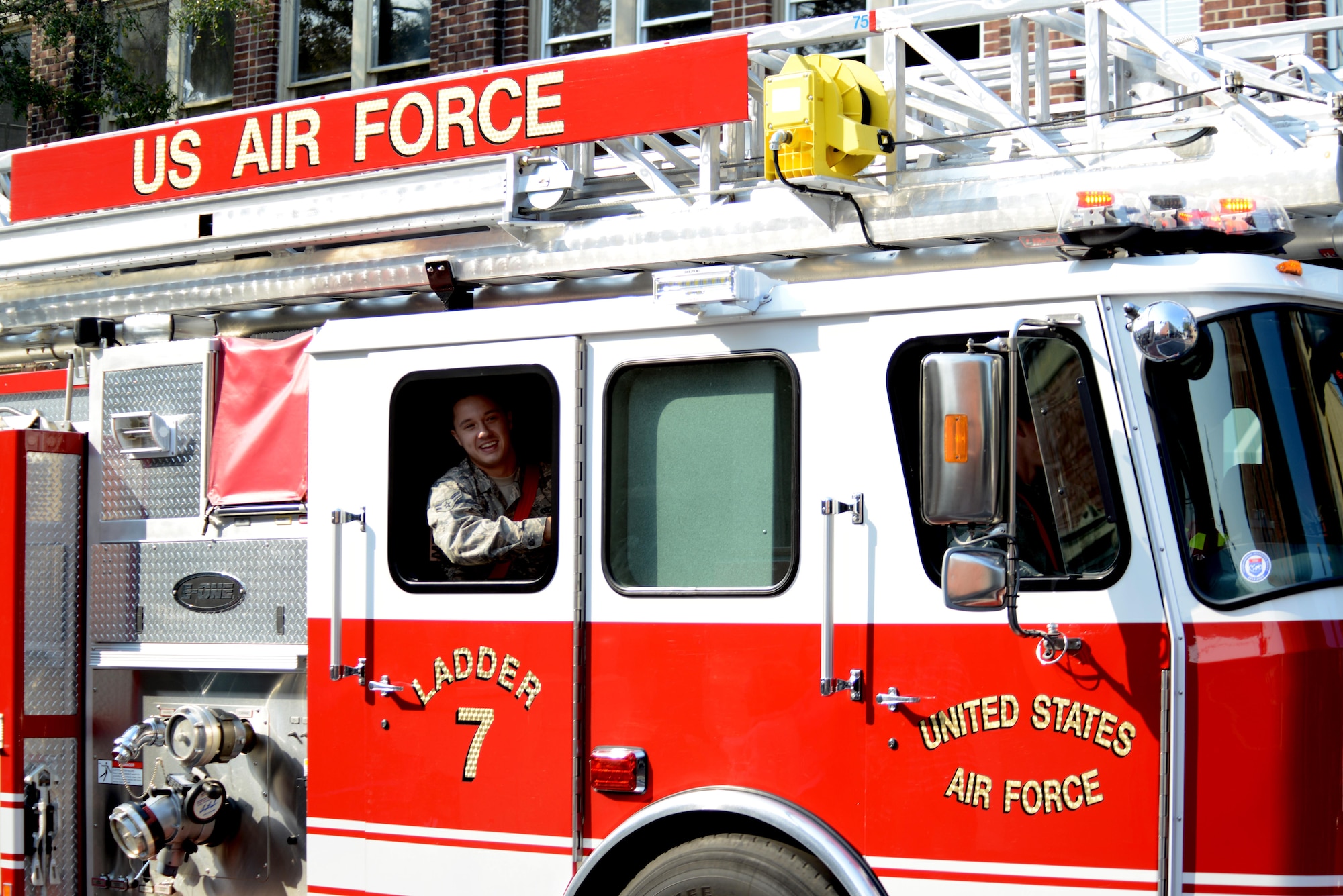 A U.S. Airman assigned to the 20th Civil Engineer Squadron fire and emergency services flight tosses candy to the crowd during a Veterans Day parade, Sumter, S.C., Nov. 11, 2016. Several vehicles from Shaw Air Force Base, S.C., participated in the parade in addition to a formation of Airmen, including a fire engine, an ambulance, and Humvees from U.S. Army Central. (U.S. Air Force photo by Airman 1st Class Kelsey Tucker)