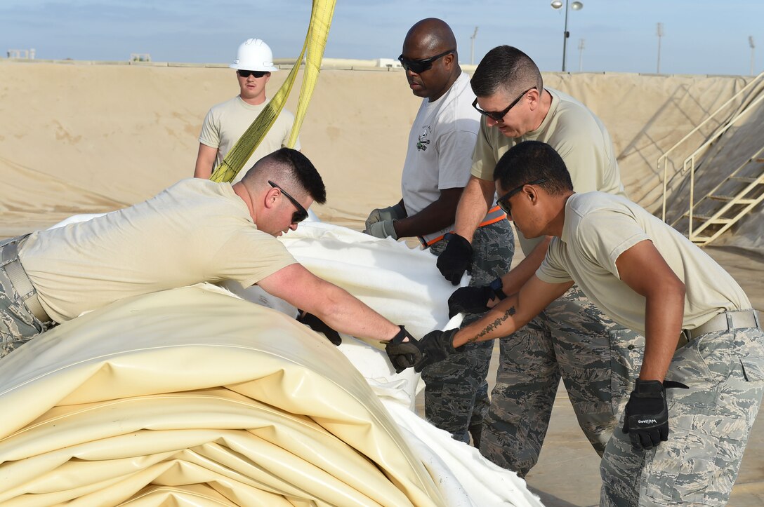 Members of the 380th Expeditionary Logistics Readiness Squadron remove the protective shipping cover from a new fuel bladder at an undisclosed location in Southwest Asia, Nov. 9, 2016. The cover has to be removed before crane operators leave in case the bladder needs to be moved so that it rolls out in the correct direction. (U.S. Air Force photo by Tech. Sgt. Christopher Carwile) 