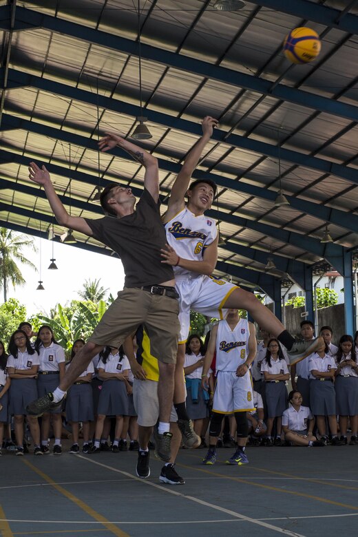U.S. Marine Corps Lance Cpl. Austin Barron, an aviation maintainer with Marine Aviation Logistics Squadron (MALS) 12, and a Sekolah Menengah Eben Haezar Manado High School student jump for a basketball in Manado, Indonesia, Nov. 9, 2016. The Marines and Sailors played basketball against the school basketball teams, losing 50-22 after playing three games. As part of a community relations event, the visit offered service members the opportunity to engage in cultural exchanges and build relationships within the local community. (U.S. Marine Corps photo by Cpl. Aaron Henson)