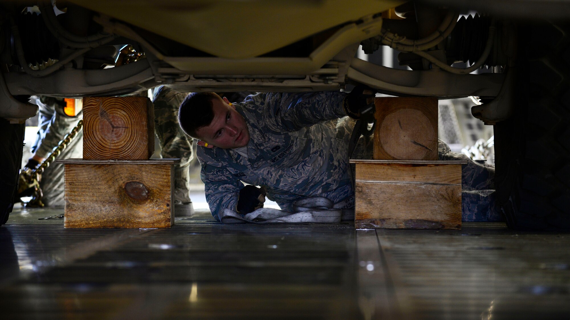 Airman Skylar Keyes, 724th Air Mobility Squadron aircraft services specialist, places load-bearing supports underneath an all-terrain vehicle at Aviano Air Base, Italy on Nov. 8, 2016. Thirteen 724th AMS personnel loaded the vehicles, secured them with chains, and made sure the cargo weight was evenly distributed for transport to Iraq. (U.S. Air Force photo by Senior Airman Cary Smith)