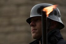 A German soldier donning a traditional Germany army helmet holds a torch during a German National Day of Mourning observance ceremony at the Kolmeshöhe Military Cemetery in Bitburg, Germany, Nov. 13, 2016. The day, known as Volkstrauertag in German, observes the human cost of war and was established following the conclusion of the First World War. (U.S. Air Force photo by Staff Sgt. Joe W. McFadden)