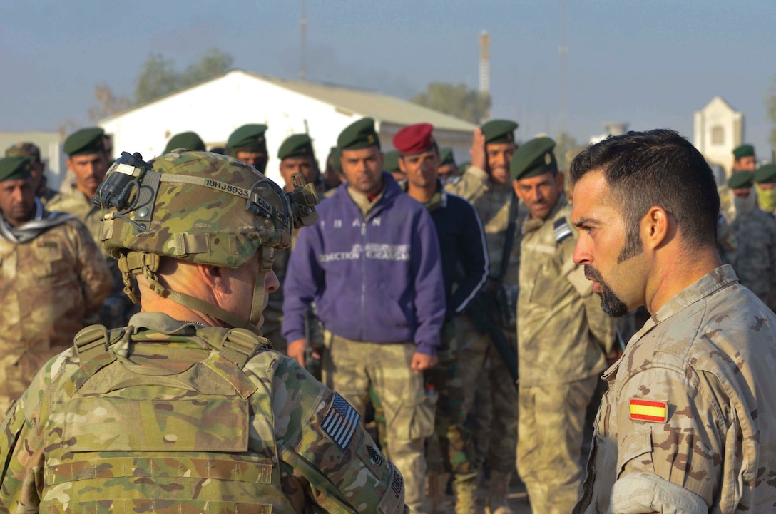 Command Sgt. Maj. Benjamin Jones of Combined Joint Task Force-Operation Inherent Resolve, speaks with a Coalition trainer from Spain during his visit to the Besmaya Building Partner Capacity (BPC) site November, 2016.  Training at the building partner capacity sites is an integral part of Combined Joint Task Force – Operation Inherent Resolve’s multinational effort to train Iraqi Security Force personnel to defeat the Islamic State of Iraq and the Levant.  The mission of Operation Inherent Resolve is to defeat Da’esh (an Arabic acronym for ISIL) in Iraq and Syria by supporting the Government of Iraq with trainers, advisors and fire support, to include aerial strikes and artillery fire.  (U.S. Army photo by Spc. Ethan Hutchinson/Released)