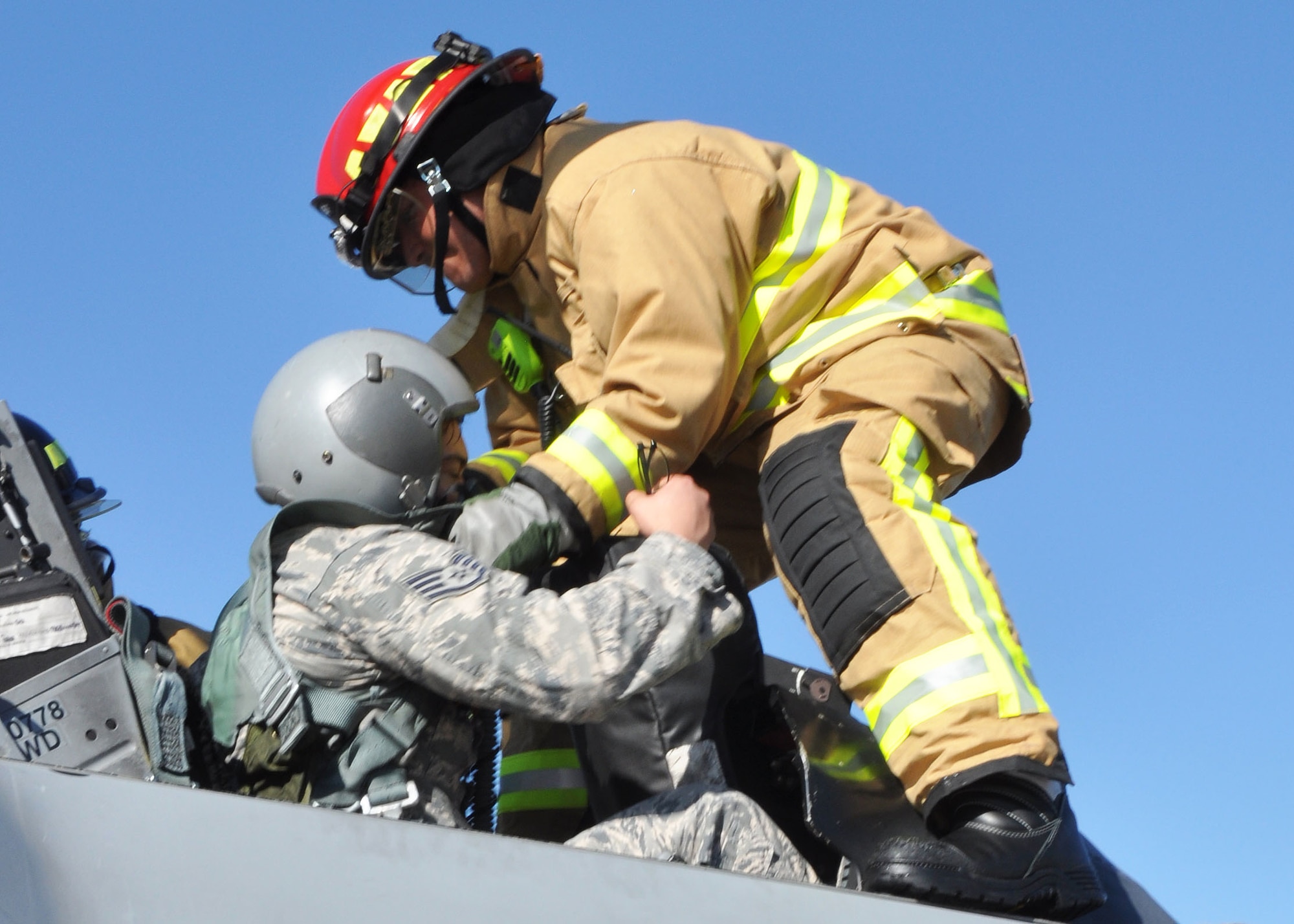 Tech. Sgt. Gabe Ulibarri, 944th Civil Engineer Squadron firefighter, helps to extricate an Airman from a simulated burning F-16, during annual egress training during the November UTA. (U.S. Air Force photo by Tech. Sgt. Barbara Plante)