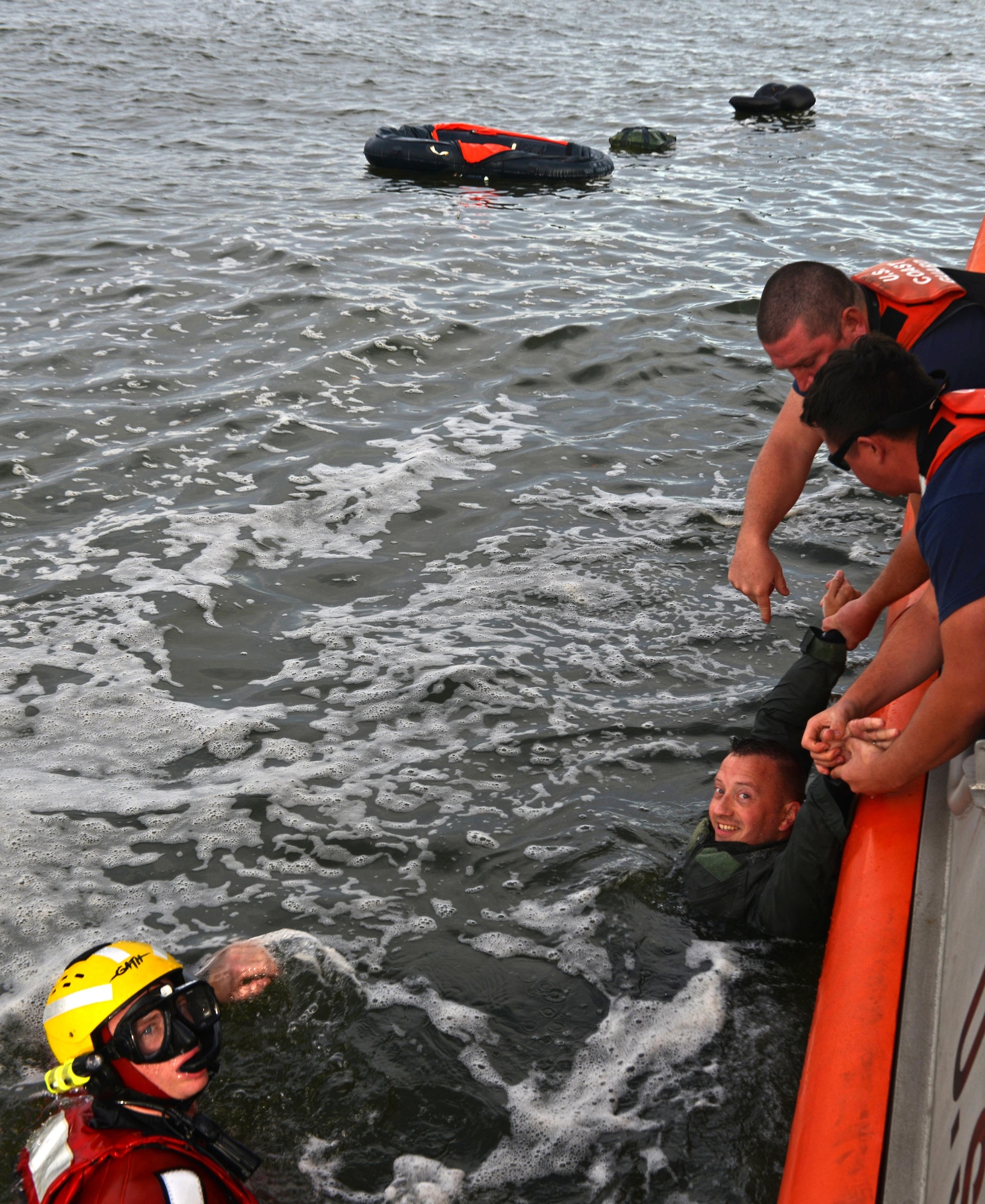 Two U.S. Coast Guardsmen pull Air Force Lt. Col. Martin Mentch, 20th Fighter Wing director of staff, onto a 45-foot response boat-medium at Coast Guard Station Tybee, Ga., Nov. 8, 2016. 20th FW pilots participated in water survival training, simulating an aircraft ejection and helicopter rescue. (U.S. Air Force photo by Airman 1st Class Destinee Sweeney)