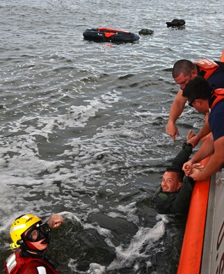 Two U.S. Coast Guardsmen pull Air Force Lt. Col. Martin Mentch, 20th Fighter Wing director of staff, onto a 45-foot response boat-medium at Coast Guard Station Tybee, Ga., Nov. 8, 2016. 20th FW pilots participated in water survival training, simulating an aircraft ejection and helicopter rescue. (U.S. Air Force photo by Airman 1st Class Destinee Sweeney)