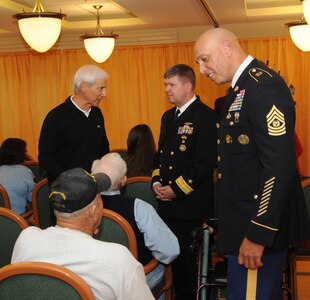 Deputy Commander of U.S. Strategic Command’s (USSTRATCOM) Joint Functional Component Command for Global Strike (JFCC-GS) Rear Adm. Thomas E. Ishee (middle) and JFCC-GS Command Sgt. Maj. Nathaniel Jett, talk to veterans during the Eastern Nebraska Veterans’ Home annual Veterans Day program in Bellevue, Neb., Nov. 11, 2016.  The program celebrated the residents who live there along with veterans worldwide. Veterans Day was originally referred to as “Armistice Day” because it was celebrated on the same date that World War I hostilities ended on the 11th hour of the 11th day of the 11th month in 1918. On June 1, 1954, President Dwight D. Eisenhower officially changed the name to Veterans Day, celebrated on Nov. 11 each year, a day to honor American veterans of all wars. (USSTRATCOM photo by Steve Cunningham) 