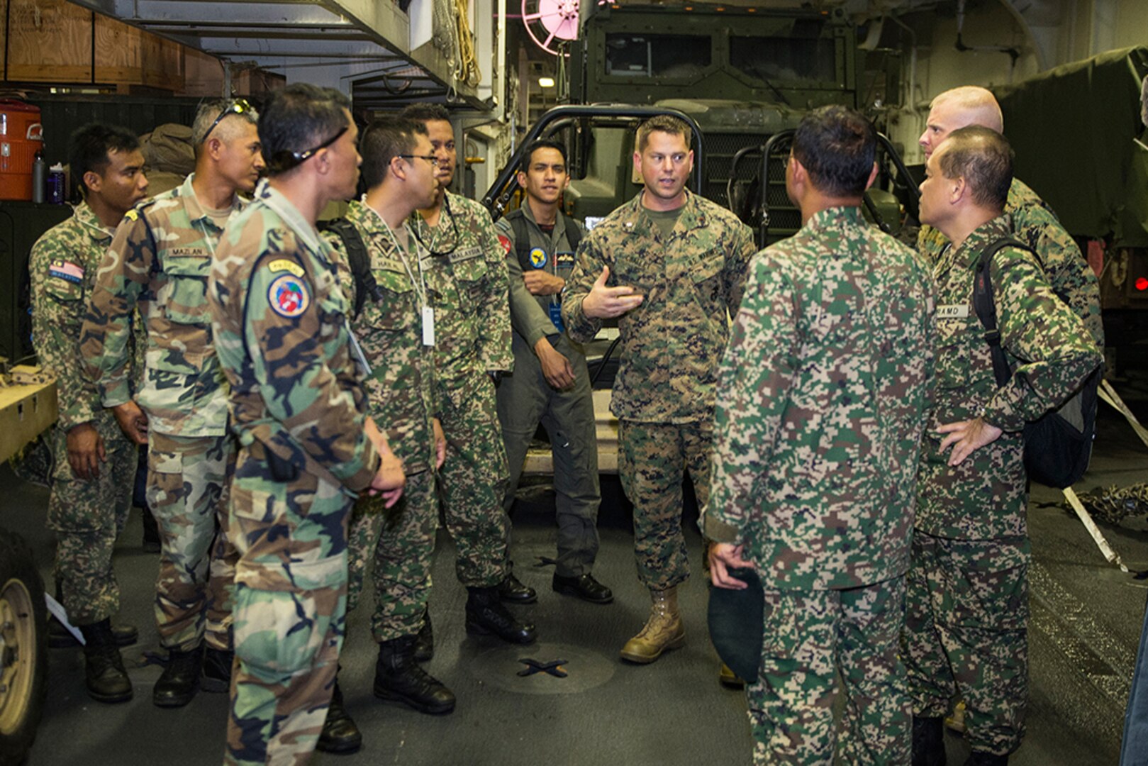 Marine Corps Chief Warrant Officer 2 Keith Challet, Combat Cargo Officer aboard the amphibious assault ship USS Makin Island (LHD 8), gives members of the Malaysian Armed Forces a tour of the ship’s upper vehicle storage during Tiger Strike 16.  Tiger Strike is a U.S.-Malaysia bilateral exercise designed to enhance interoperability, tactical proficiencies, and military-to-military partnership between participating forces. 