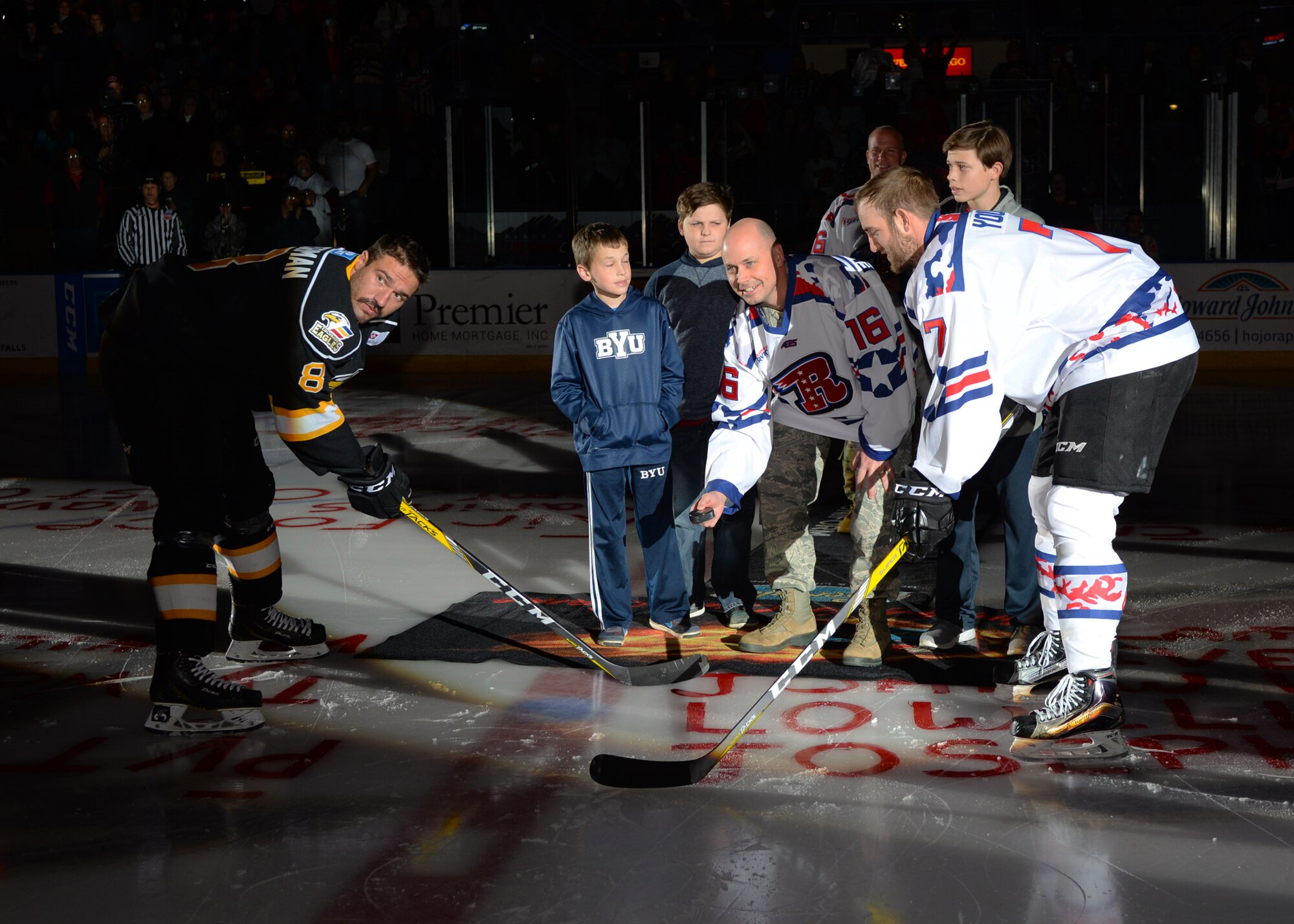Col. Bradley Cochran, vice commander of the 28th Bomb Wing, center, performs a puck drop ceremony at a Rapid City Rush hockey game at the Rushmore Plaza Civic Center in Rapid City, S.D., Nov. 12, 2016. The ceremonial puck drop was part of the team’s ninth annual Military Appreciation Night, where team members and staff pay tribute to and honor military members for their service. (U.S. Air Force photo by Airman 1st Class Denise M. Jenson)