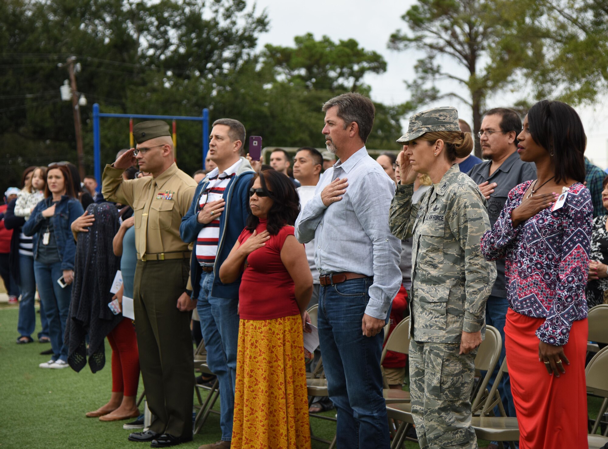 Col. Michele Edmondson, 81st Training Wing commander, and fellow audience members honor the flag during a Jeff Davis Elementary School Veterans Day Celebration Nov. 11, 2016, in Biloxi, Miss. During the event, students also sang several patriotic songs. Keesler Air Force Base Honor Guard Airmen also participated in the event. (U.S. Air Force photo by Kemberly Groue/Released)