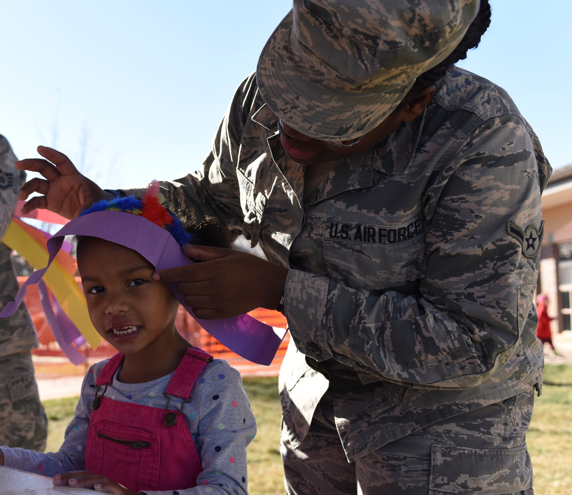 Airman Kashe Smith, a public health technician assigned to the 28th Medical Group (right), helps Sophia Stevenson (left), daughter of Tech. Sgt. Robert Stevenson and Alena Stevenson, place her headpiece during a story time and arts and crafts event at the Child Development Center at Ellsworth Air Force Base, S.D., Nov. 3, 2016. The children sat outside for a reading of “If You Lived with the Sioux Indians” and made their own paper headpieces. (U.S. Air Force photo by Airman 1st Class Randahl J. Jenson)