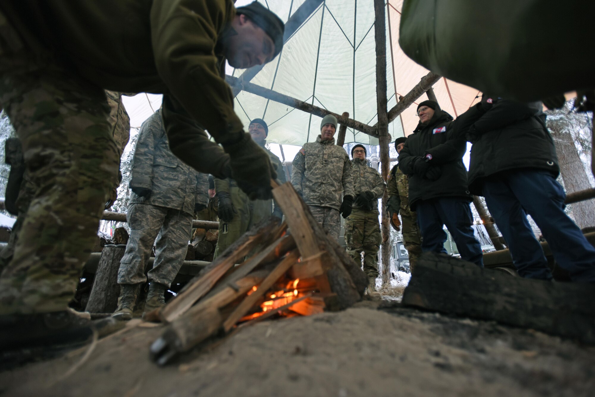 U.S. Air Force Master Sgt. Marc Richard, Arctic Cool School Survival, Evasion, Resistance, and Escape instructor, shows participants of the Arctic General Officer/Flag Officer Summit the importance of building a fire in the Arctic in order to melt snow and obtain water Nov. 9. U.S. Air Force Lt. Gen. Ken Wilsbach, Alaskan NORAD Region, Alaskan Command and 11th Air Force commander and U.S. Army Maj. Gen. Bryan Owens, U.S. Army Alaska commander hosted the conference, which included flag officers from the U.S. Air Force, U.S. Army, U.S. Coast Guard, Alaska National Guard and Canadian Forces, to strengthen partnerships, discuss future Arctic and Alaskan challenges and joint capabilities.