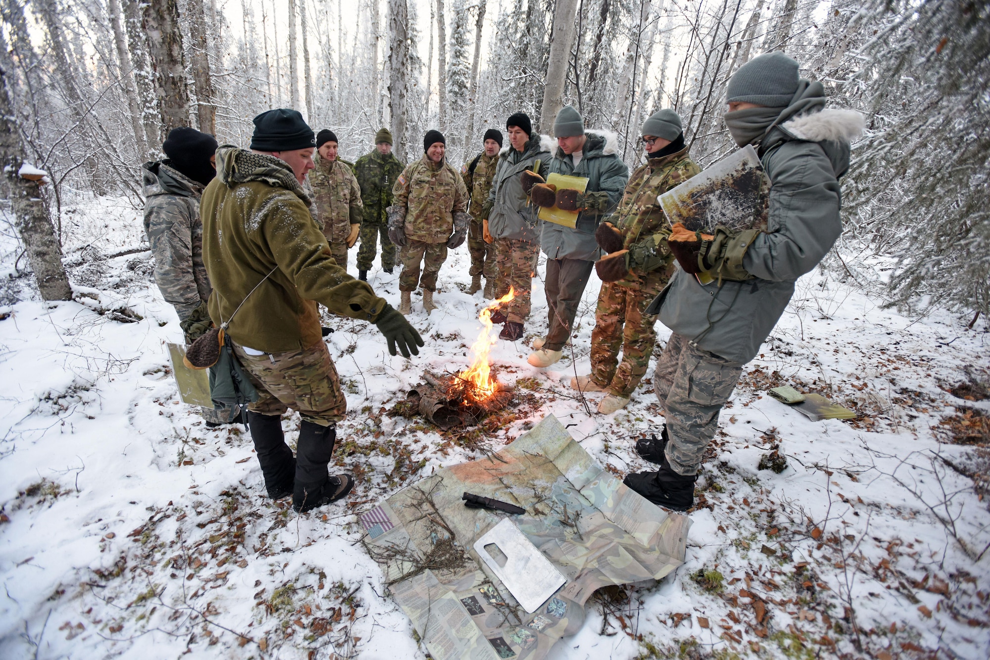 U.S. Air Force Staff Sgt. Jonathan Case (left), Arctic Cool School Survival, Evasion, Resistance, and Escape instructor, shows participants of the Arctic General Officer/Flag Officer Summit materials that are provided to Arctic Cool School students and what they can do with them in order to survive and thrive in the Arctic Nov. 9. U.S. Air Force Lt. Gen. Ken Wilsbach, Alaskan NORAD Region, Alaskan Command and 11th Air Force commander and U.S. Army Maj. Gen. Bryan Owens, U.S. Army Alaska commander hosted the conference, which included flag officers from the U.S. Air Force, U.S. Army, U.S. Coast Guard, Alaska National Guard and Canadian Forces, to strengthen partnerships, discuss future Arctic and Alaskan challenges and joint capabilities.