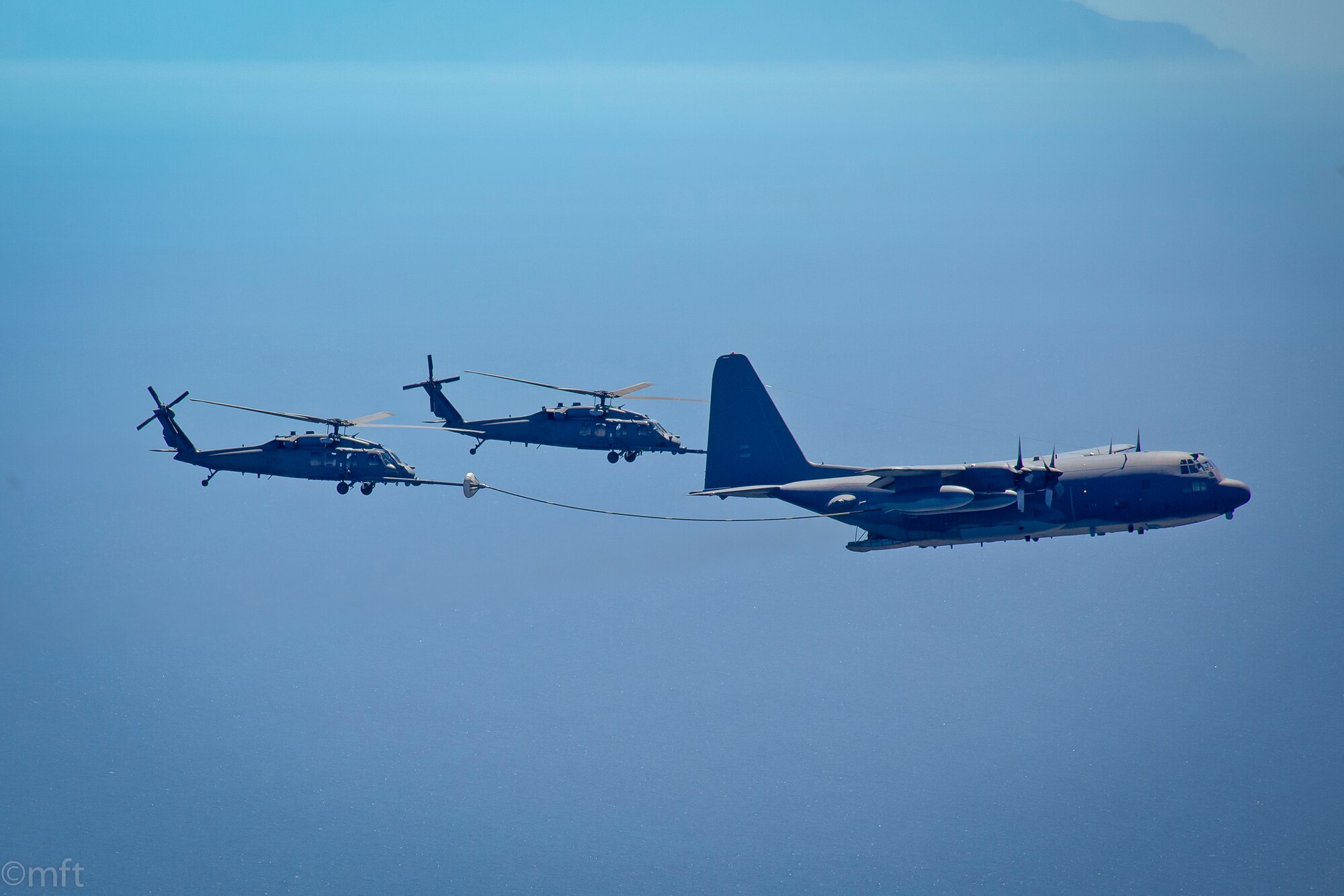 Two HH-60G Pave Hawk rescue helicopter and an MC-130P Combat Shadow aircraft, assigned with the 129th Rescue Wing, California Air National Guard, conduct an aerial refuel operations over the pacific ocean, April 3, 2014.  (Courtesy photo by Master Sgt. Miguel Toro/released)