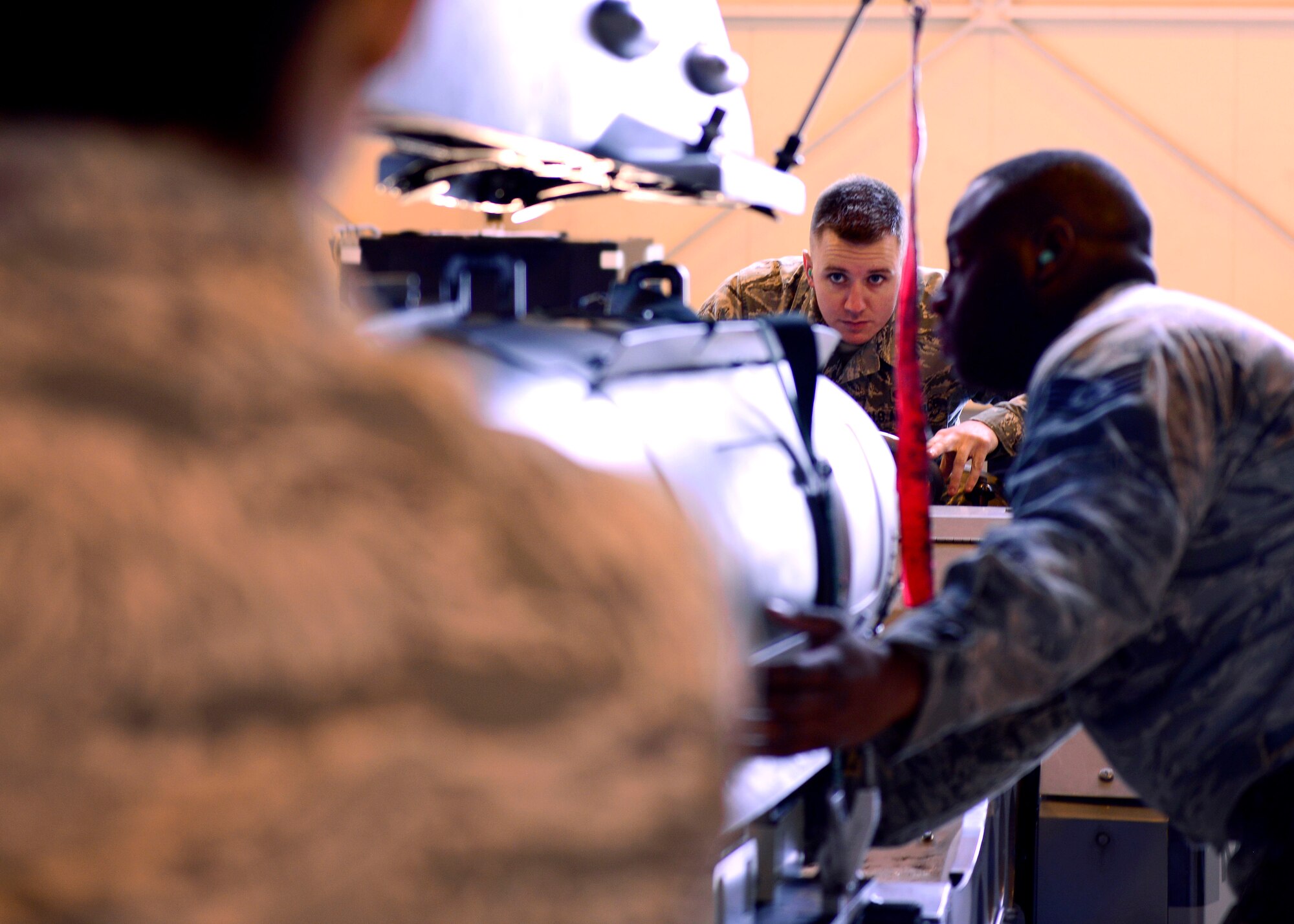 Airman 1st Class Kaleb Linn, 31st Aircraft Maintenance Squadron weapons load crew member, and Staff Sgt. Tyrral Leach, 31st AMXS weapons load crew supervisor, guide ordnance onto an F-16 Fighting Falcon during a weapons loading demonstration at Aviano Air Base, Italy on Nov. 11, 2016. Weapons load crew members inspect the F-16 before and after the munitions are loaded. (U.S. Air Force photo by Senior Airman Areca T. Bell)
