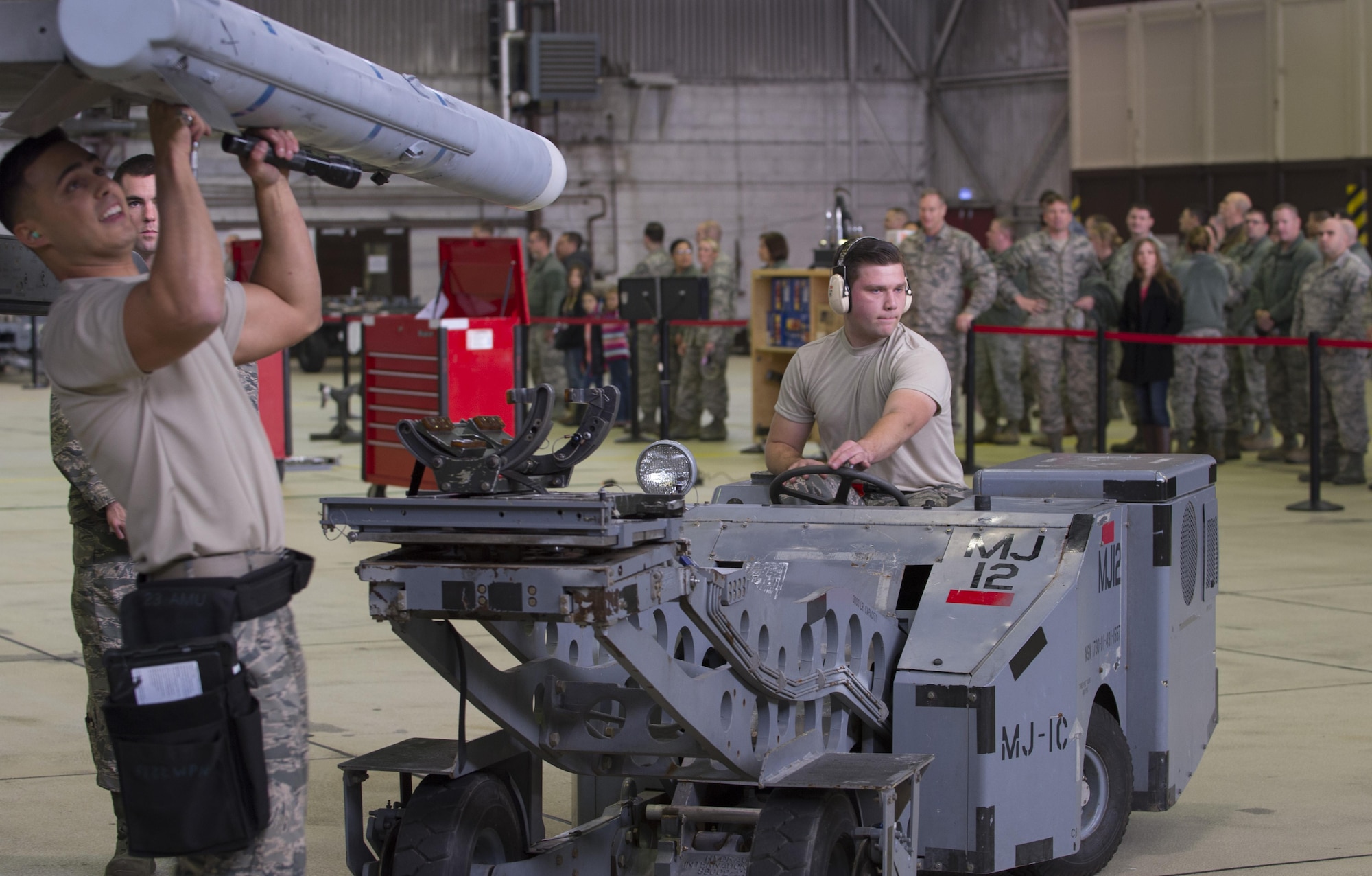U.S. Air Force Staff Sgt. Daniel Vazquez, left, and Airman 1st Class Christian Edson, right, both 52nd Aircraft Maintenance Squadron tactical aircraft weapons systems specialist, members of one of the load competition teams work to load a dummy weapon on to an F-16 Fighting Falcon during the quarterly weapons load competition in Hangar One on Spangdahlem Air Base, Germany, Nov. 10, 2016. Family, friends and members of the Spangdahlem community attended the competition to see which of the two teams of three maintenance Airmen would move on to the annual load competition. (U.S. Air Force photo by Senior Airman Dawn M. Weber)