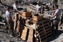 Members of the 386th Expeditionary Civil Engineer Squadron Explosive Ordnance Disposal flight make final adjustments to a pile of unserviceable ammunition at an undisclosed location in Southwest Asia Nov. 9, 2016. After all the ammunition is added, the EOD flight will bury it under more dirt before lighting the boxes on fire. (U.S. Air Force photo by Senior Airman Andrew Park)