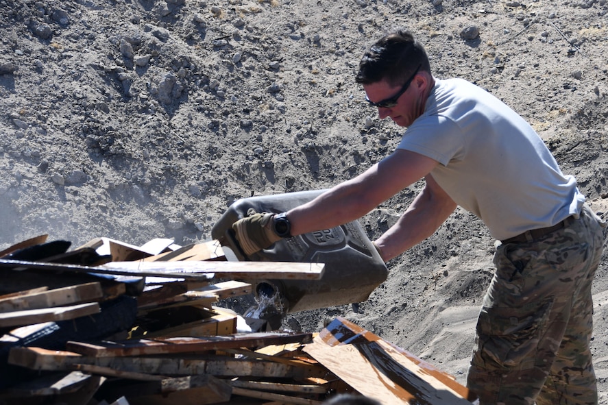 Tech Sgt. Daniel Hipps, 386th Explosive Ordnance Disposal team leader, pours fuel onto a munitions burn pile in preparation to destroy unserviceable ammunition at an undisclosed location in Southwest Asia Nov. 9, 2016. (U.S. Air Force photo by Senior Airman Andrew Park)