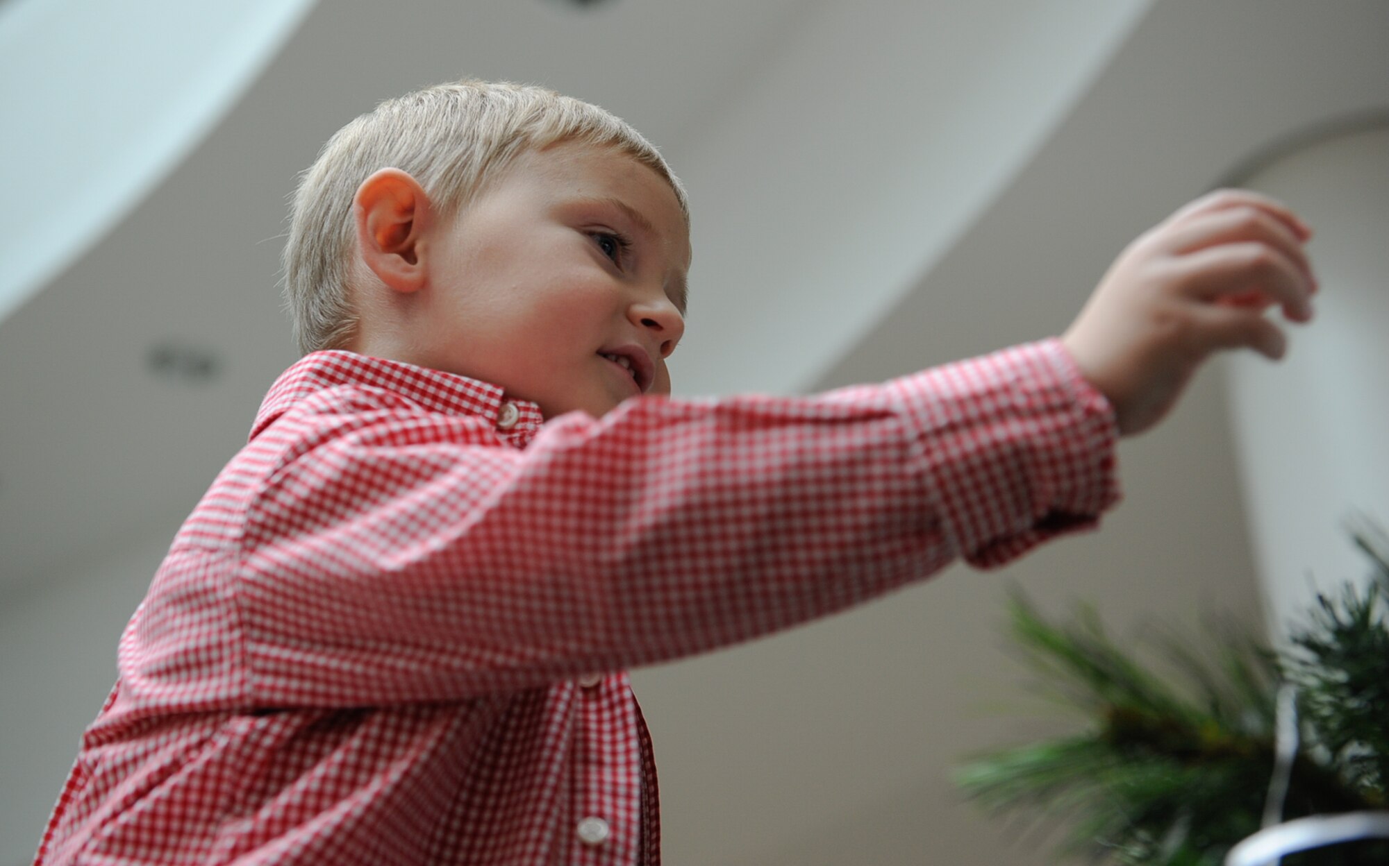 Wyatt Jacobs, son of Chief Master Sgt. Taylor Jacobs, 21st Operational Weather Squadron superintendent, reaches to adjust an angel on a tree at the 2016 Angel Tree ceremony at Ramstein Air Base, Germany, Nov. 8, 2016. Air Force first sergeants throughout the Kaiserslautern Military Community gathered at the Kaiserslautern Military Community Center to kick off the ceremony, handing out gifts to Airmen afterwards as random acts of kindness. (U.S. Air Force photo by Airman 1st Class Savannah L. Waters)