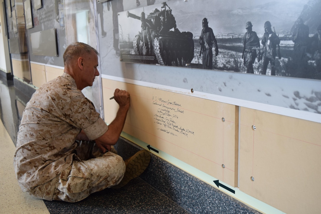 Lt. Gen. Rex C. McMillian, commander of Marine Forces Reserve and Marine Forces North, signs his name on the base board of the Marine Corps Reserve Centennial wall display at the Pentagon, Arlington, Va., Sept. 27, 2016, before the final segment is installed. The exhibit was installed at the Pentagon in conjunction with the 100th anniversary of the Marine Corps Reserve, which was celebrated Aug. 29, 2016. For more information on the history and heritage of the Marine Corps Reserve as well as current Marine stories and upcoming Centennial events, please visit www.marines.mil/usmcr100.