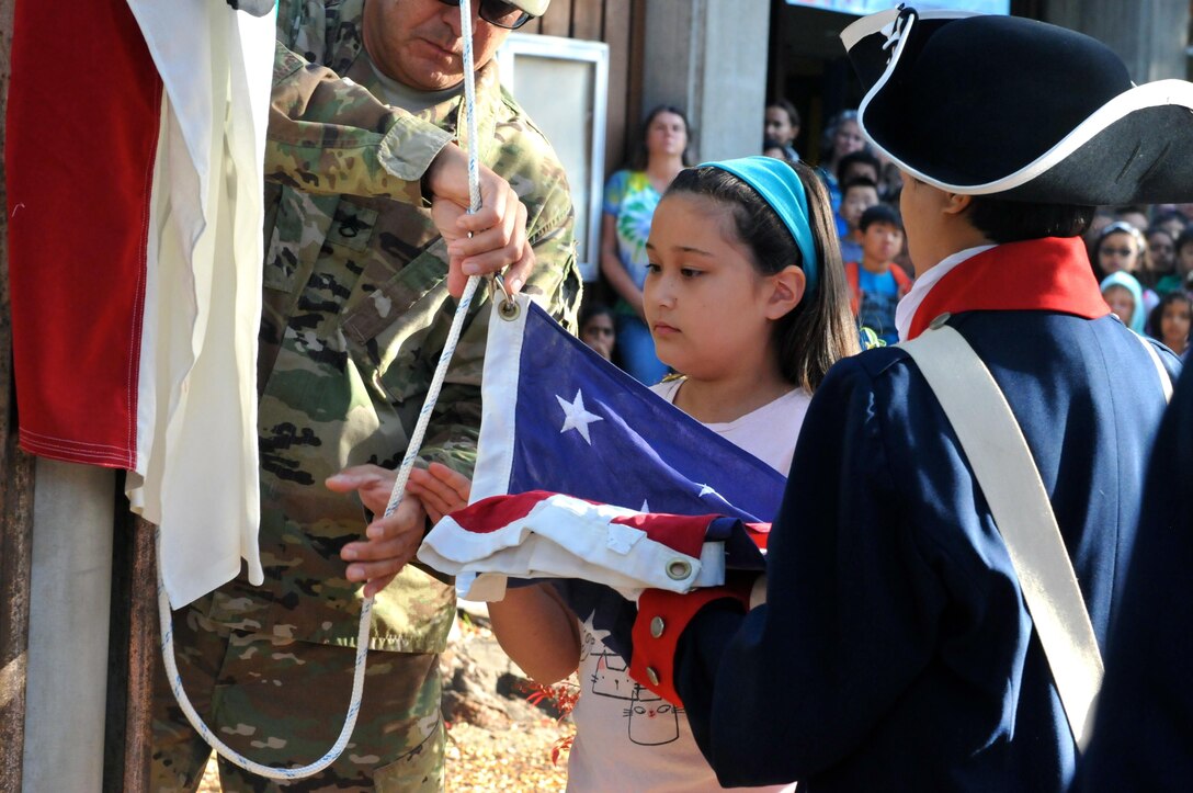 Assisted by Sgt. Arleen Banioza (right), color guard noncommissioned officer, 63rd Regional Support Command, and Staff Sgt. Juan Martinez (left), senior human resource specialist, 63rd RSC, fourth grader Amy Pietromanco (center) helps raise the U.S. flag during a flag raising ceremony, Nov. 10, Christa McAuliffe Elementary School, Saratoga, Calif. (U.S. Army Reserve photo by Alun Thomas, 63rd RSC Public Affairs)