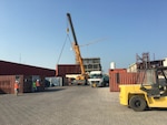 A crane at DLA Distribution Bahrain prepares to load one of the first of five trucks that will be transporting supplies using the emerging Trans-Arabian Network routes.