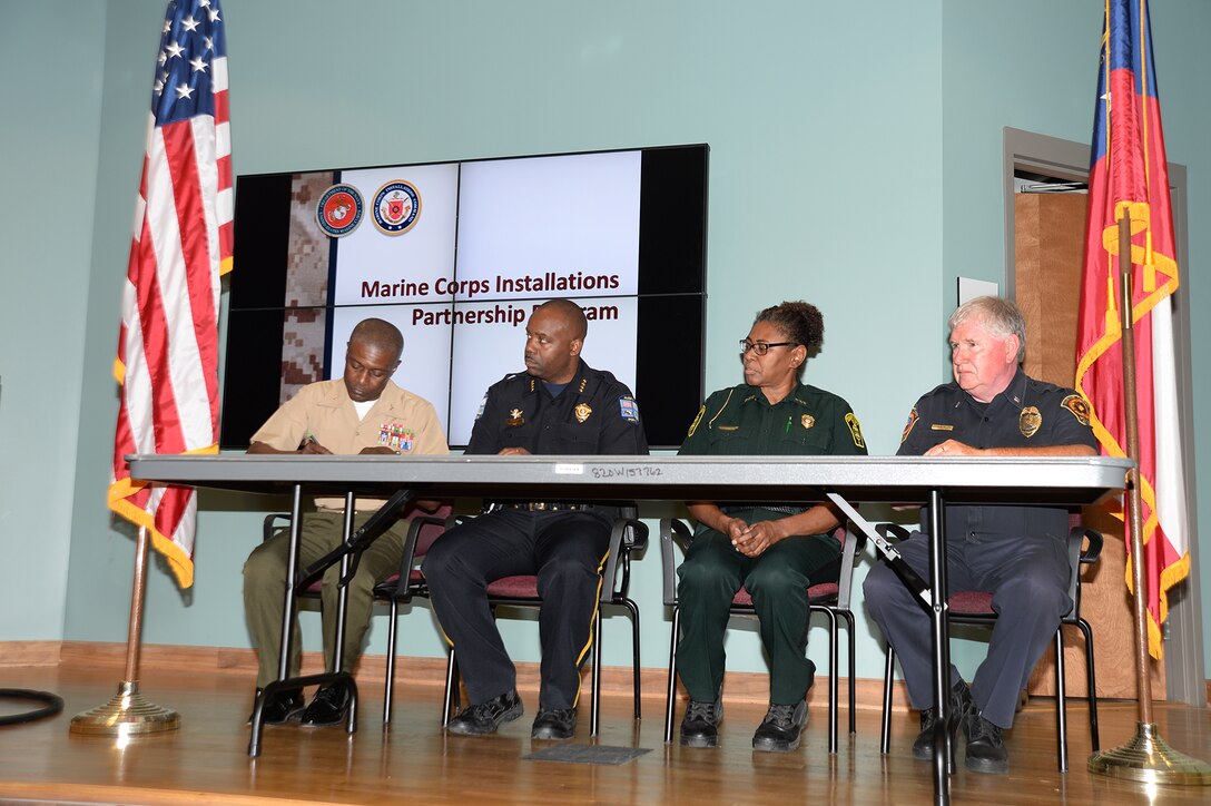 Col. James C. Carroll III, commanding officer, Marine Corps Logistics Base Albany, left, signs the S.W.A.T. partnership agreement along with three other chiefs of police; (from left) Michael Persley, City of Albany; Cynthia Battle, Dougherty County; Randy Jack, Marine Corps Police Department, at Albany Technical College, Albany, Ga., recently.

