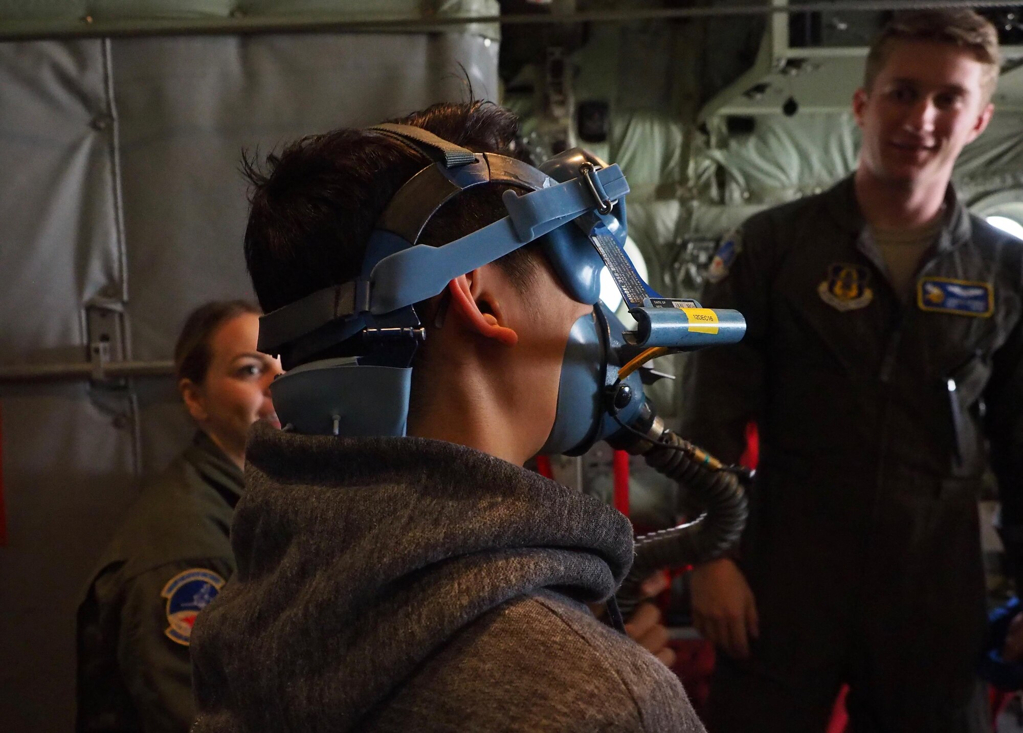 A member of the Ames High School orchestra tries on an oxygen mask aboard a C-130 as Staff Sgt. Hannah Currie and Senior Airman James Dennis, 934th Aeromedical Evacuation Squadron, look on.        
