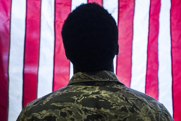 An Airman stands in front of an American Flag hanging in a KC-10 Extender during the Aviation Nation air show on Nellis Air Force Base, Nev., Nov. 12, 2016. The KC-10's primary mission is aerial refueling, it can combine the tasks of a tanker and cargo aircraft by refueling fighters and simultaneously carry the fighter support personnel and equipment on overseas deployments. (U.S. Air Force photo by Airman 1st Class Kevin Tanenbaum/Released)
