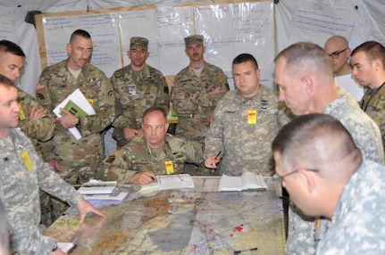 New York Army National Guard aviation Soldiers assigned to the 42nd Combat Aviation Brigade ponder their next move over a map of the area of operations in their command post during a two-week Warfighter command post exercise at Fort Indiantown Gap on Thursday, Nov. 10, 2016. The exercise is testing the staff skills the Soldiers need to handle a variety of complex aviation missions. 