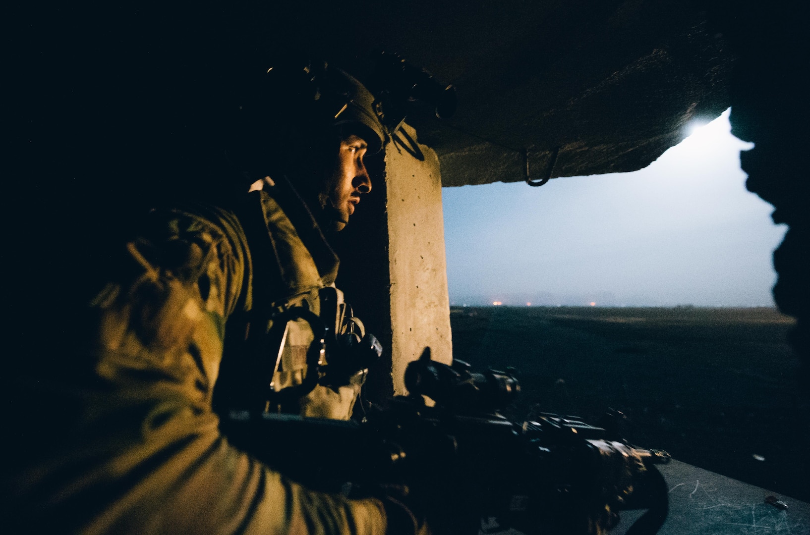 Senior Airman Ralph Hoeflich, 821st Contingency Response Group close precision engagement airman, scans a field illuminated by a flare from inside a defensive fighting position at Qayyarah West Airfield, Iraq, in support of Combined Joint Task Force - Operation Inherent Resolve, Nov. 14, 2016. The 821st CRG is highly-specialized in training and rapidly deploying personnel to quickly open airfields and establish, expand, sustain and coordinate air operations in austere, bare-base conditions. (U.S. Air Force photo by Senior Airman Jordan Castelan)