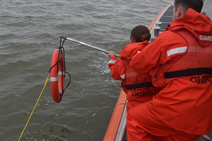 U.S. Coast Guard Fireman Gabrielle Marshall, left, and Fireman David Deaton, right, recover a life preserver from the water during training Nov. 14, 2016, at USCG Sector Charleston, South Carolina. The floatation device, equipped with a GPS, was deployed during a man overboard training exercise to record the rescue time. The goal is to accomplish a successful rescue in less than two minutes. 