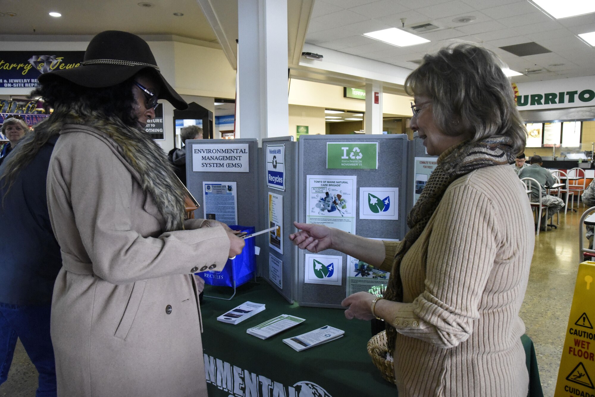 Diane Wulf, 92nd Civil Engineer Squadron pollution prevention program manager, hands a recycling brochure and pencil to a shopper during National Recycling Day Nov. 15, 2016, at Fairchild Air Force Base, Wash. The recycling process starts with giving used materials labeled as recyclables over to a local waste facility in designated disposal containers. Recyclable materials are then taken to be reused as raw materials for new products. (U.S. Air Force photo/Airman 1st Class Taylor Shelton)