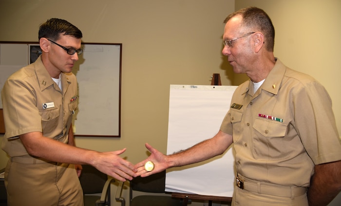 Navy Rear Admiral Kenneth Iverson, commander, Navy Medicine East (right), presents Navy Lieutenant Jonathan Carmack, quality management assistant for Naval Health Clinic Charleston, South Carolina, a coin Nov. 15, 2016. During Iverson's visit to NHCC, he recognized and engaged with Department of the Navy and Veterans Affairs personnel while touring the joint ambulatory care clinic. 