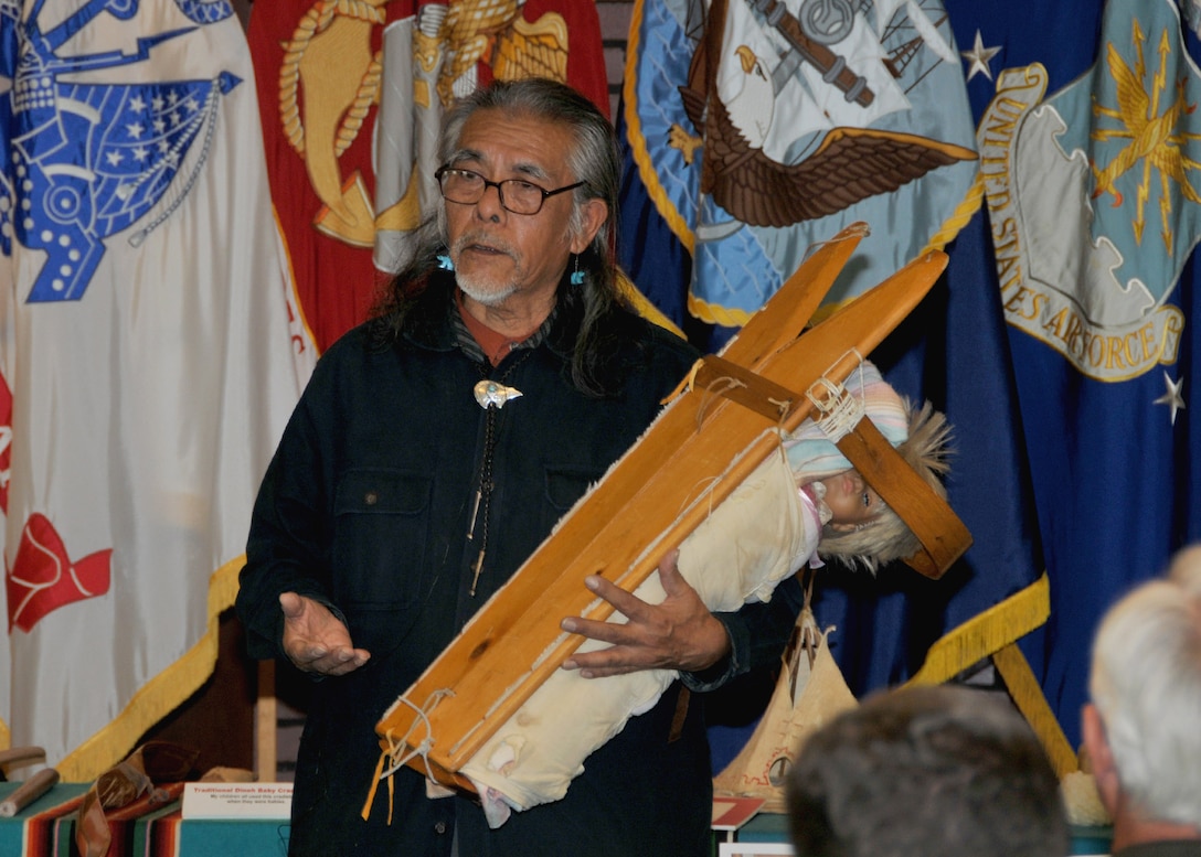 Frederick Tsinnie demonstrates a Navaho baby carrier at a Nov. 16 observance of National American Indian Heritage Month. The wooden pieces each represent aspects of human existence, as well as the natural world.