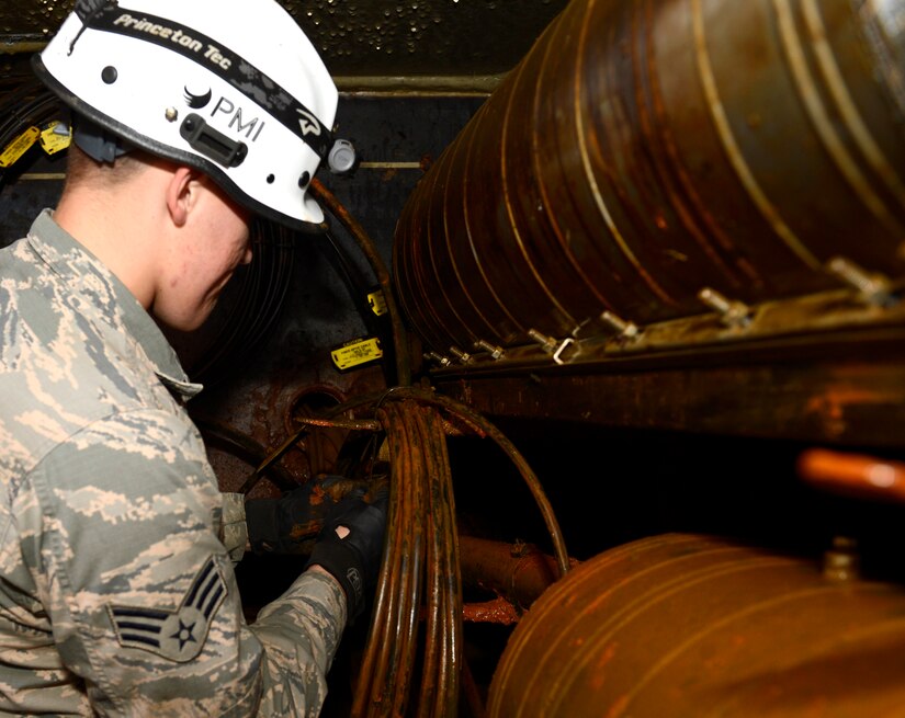 U.S. Air Force Senior Airman Bruce Winsemius, 633rd Communication Squadron cable and antenna technician, ties a group of cables together during a preventive maintenance and inspection at Joint Base Langley-Eustis, Va., Nov. 15, 2016. The 633rd CS Airmen ensure cables across base are up to standards and that the conditions of the manholes are acceptable. (U.S. Air Force photo by Kaylee Dubois)
